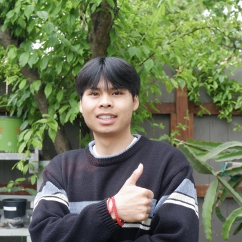 Brandon is standing in the middle of the frame, facing the camera and smiling. 
